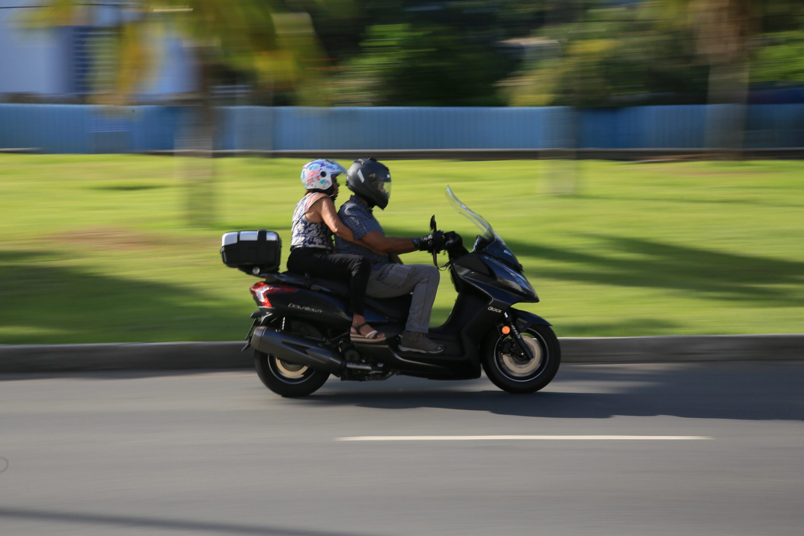 motorcycle - Warshafsky Law Firm Milwaukee, Wisconsin - Warshafsky Law Firm Milwaukee, Wisconsin A couple rides a black scooter on a road, both wearing helmets, with a blurred green and blue background indicating speed. Warshafsky Law Firm Milwaukee, Wisconsin Warshafsky Law Firm Milwaukee, Wisconsin